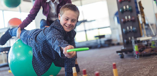 student on exercise ball playing ring toss game