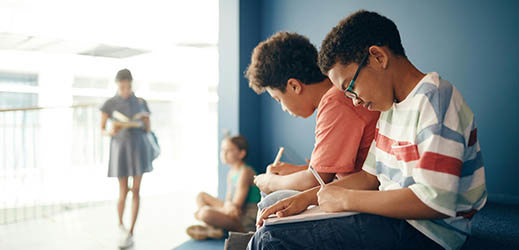 students writing in notebooks while sitting in alcove